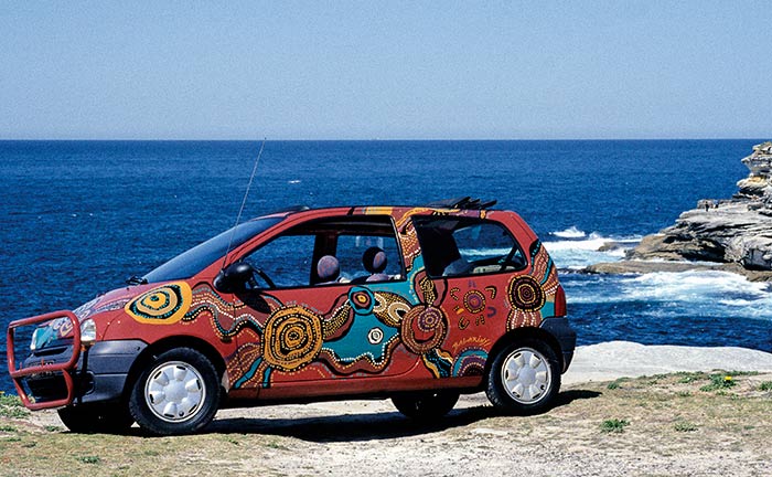 The Twingo stands on rocks with the sea in the background.