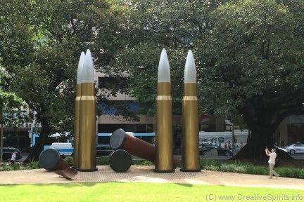 A man takes a picture of the oversized ammunition shells.