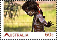 A young Aboriginal boy with body paint performs dance moves.