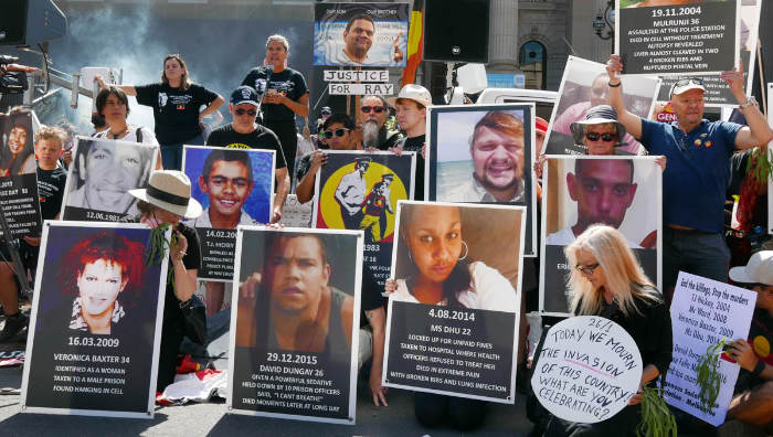Family, relatives and friends hold placards of Aboriginal people who died in custody.